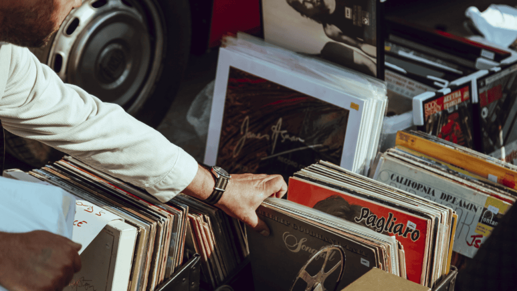 Hand browsing through a collection of vinyl records at a market