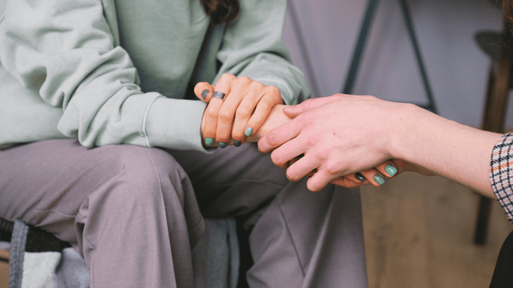 A close-up of two individuals holding hands, symbolizing emotional support and connection.