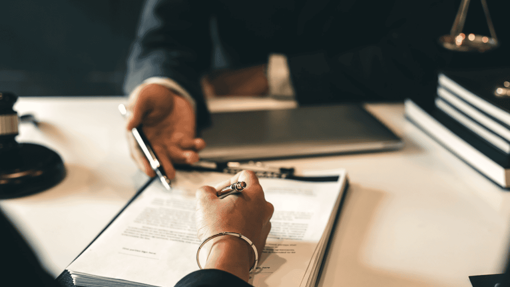 Close-up of hands signing legal documents with a pen.
