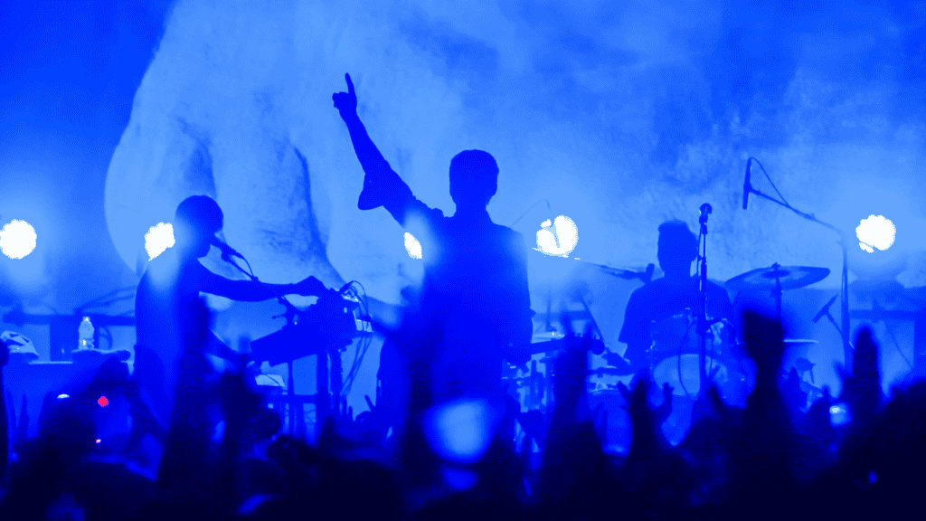 Band performing live on stage with dramatic lighting.