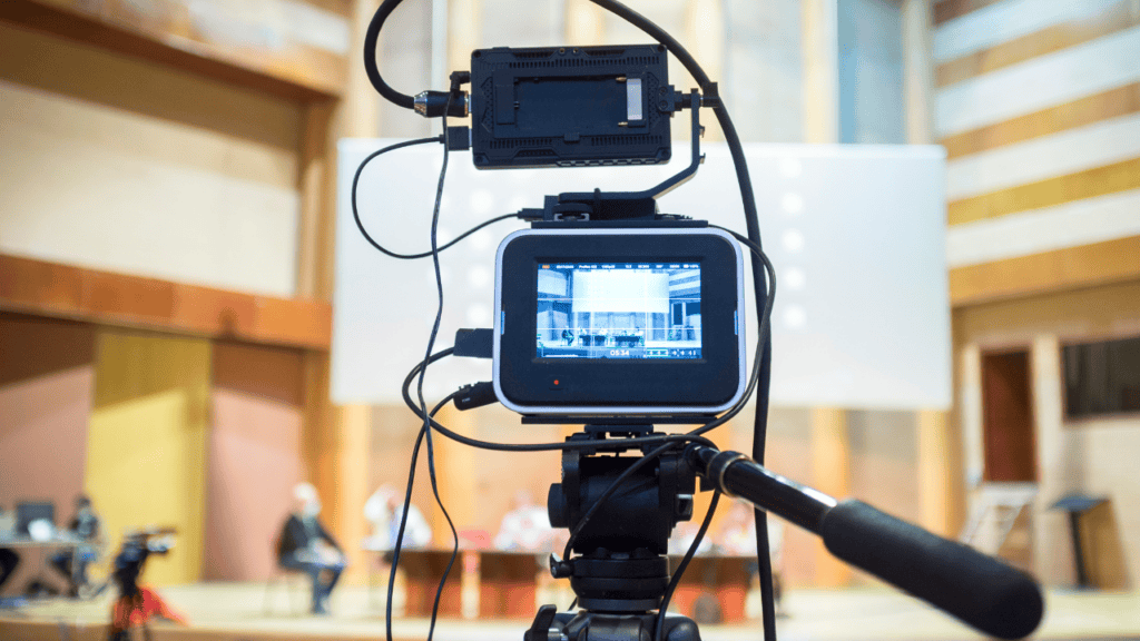 Professional camera recording a live-streamed event in a conference venue.