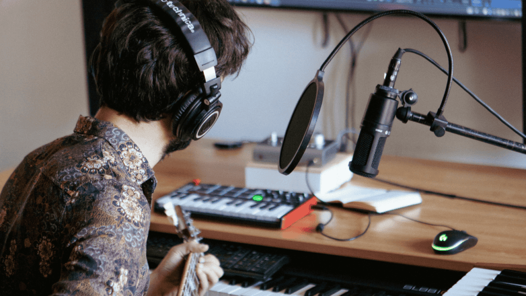 Music producer recording guitar in a home studio with a microphone.