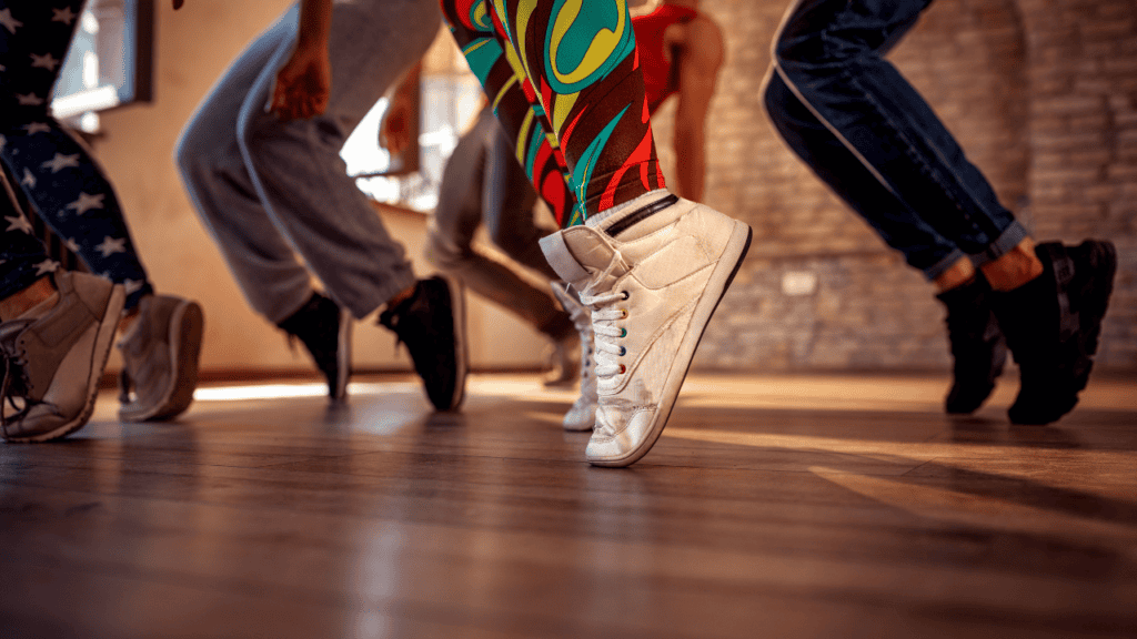 A close-up of dancers’ feet moving in sync, practicing Amapiano dance steps in a studio.