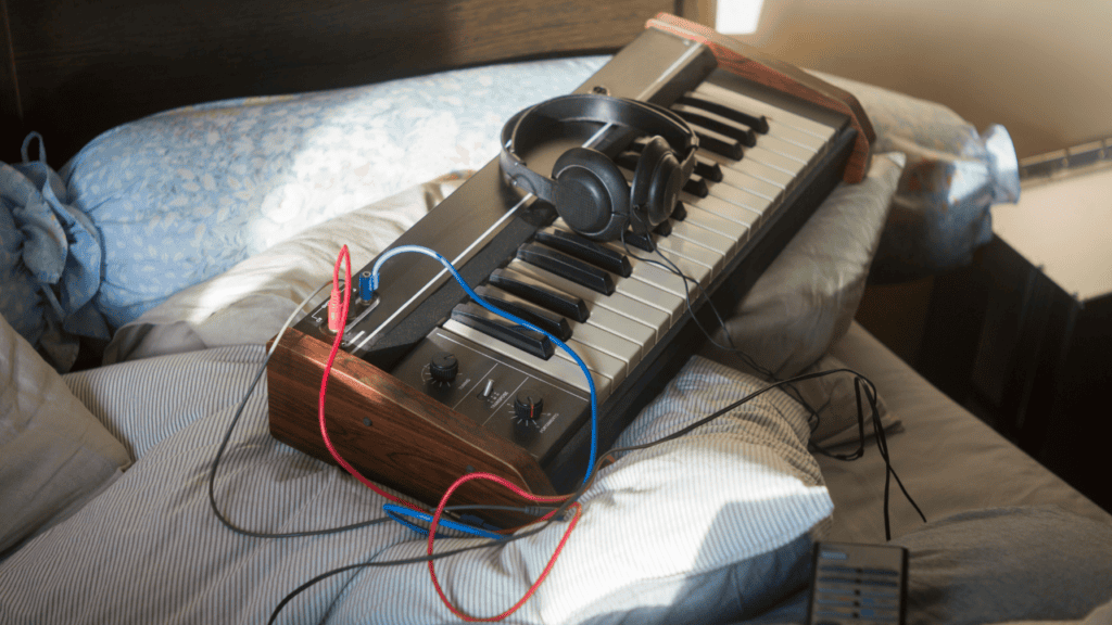 A small keyboard with headphones resting on a bed, capturing a relaxed lo-fi production vibe.