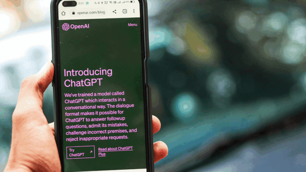 Person holding a smartphone displaying the OpenAI ChatGPT blog page.
