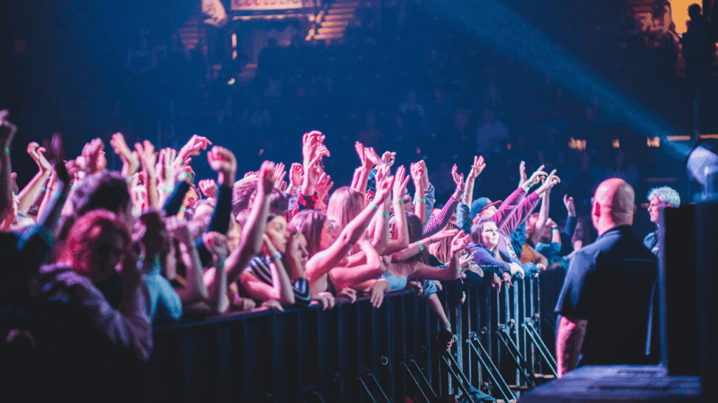 Audience at a concert raising their hands and reaching for the artist