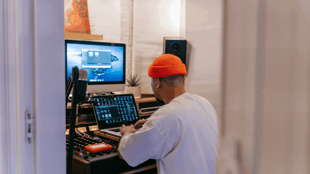 Music producer setting up projects on laptop and monitor