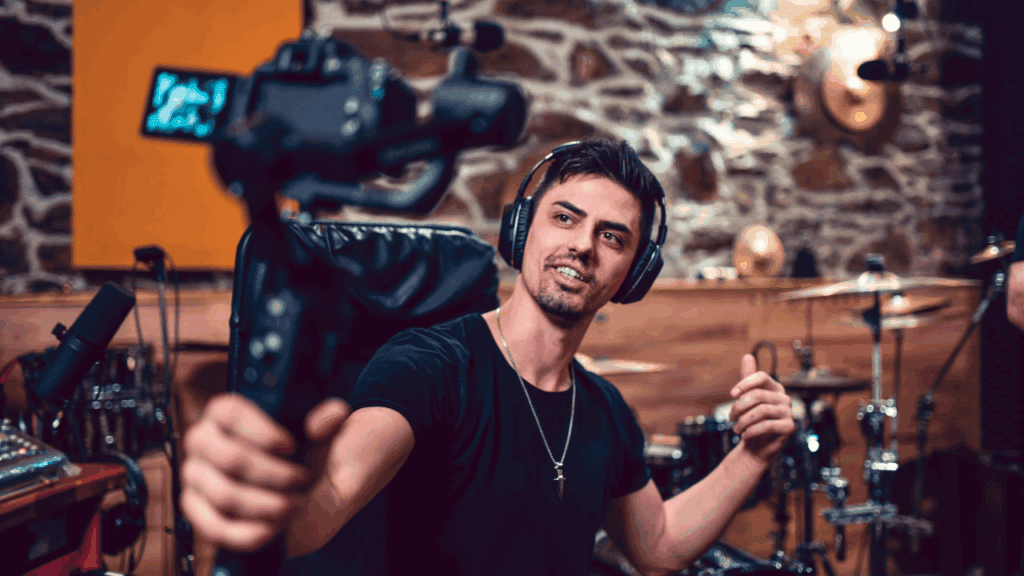 Male music producer wearing headphones and recording a vlog in his studio